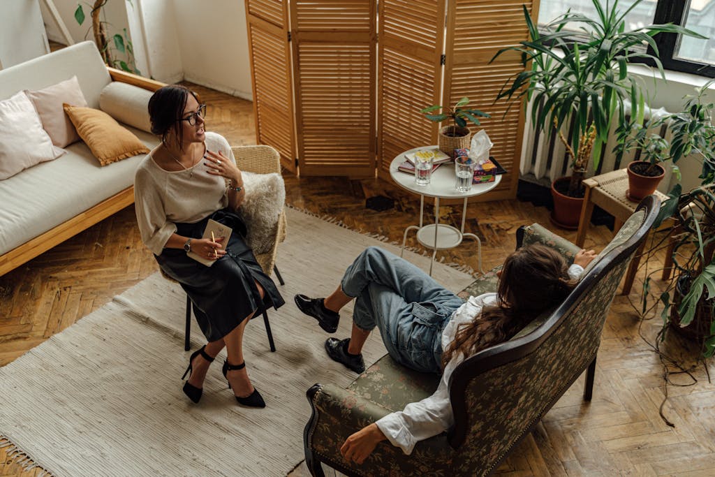 Woman in White Long Sleeve Shirt Sitting on Brown Wooden Armchair